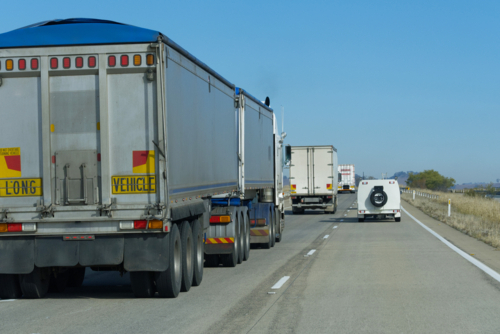 Utility overtaking long trucks on a sunny day - Australian Stock Image