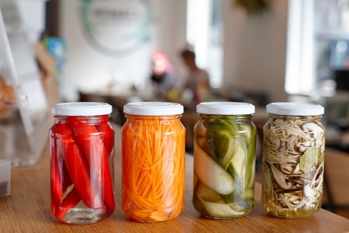 Variety of pickle jars lined up on counter in cafe - Australian Stock Image