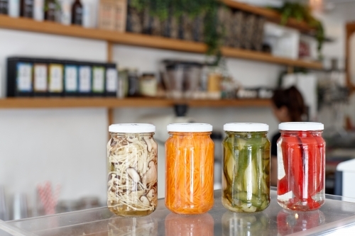 Variety of pickle jars lined up on counter in cafe - Australian Stock Image