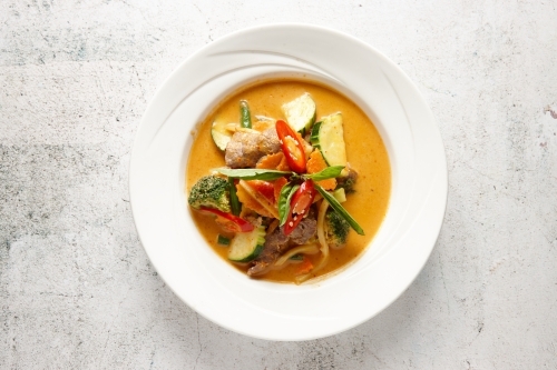 Vegetable red curry in a bowl topped with basil and chili - Australian Stock Image