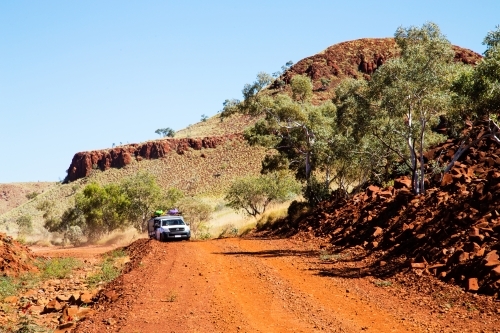 vehicle travelling on dirt road through rugged hills - Australian Stock Image