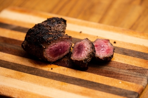 Venison cooked and cut on a timber chopping board - Australian Stock Image