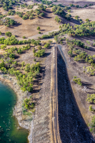 Vertical Aerial view of the access road onto the Glenbawn Dam wall with surrounding landscape in NSW - Australian Stock Image