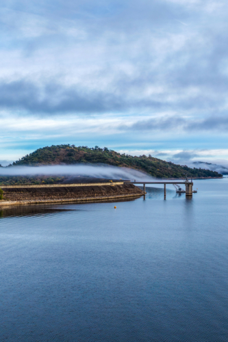 Vertical Aerial view of the Glenbawn Dam wall leading towards the surrounding mountain landscape - Australian Stock Image