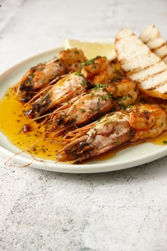 vertical close up shot of sautéed shrimps with a slice of lemon and some toast in the side - Australian Stock Image