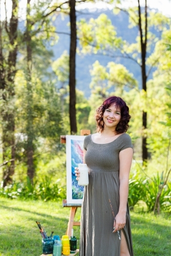 Vertical image of happy young woman smiling holding paint pot - Australian Stock Image