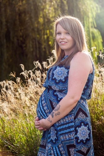 Vertical portrait of happy pregnant mother outside - Australian Stock Image