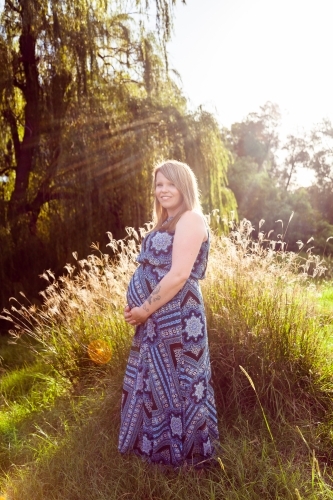 Vertical portrait of happy pregnant mother outside - Australian Stock Image