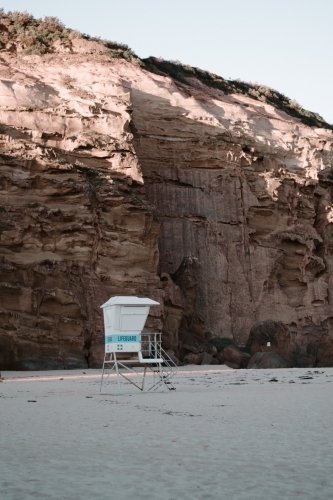 Vertical shot of a lifeguard tower with a cliff on the background.
