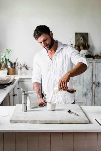 Vertical shot of a man pouring coffee on a white cup - Australian Stock Image