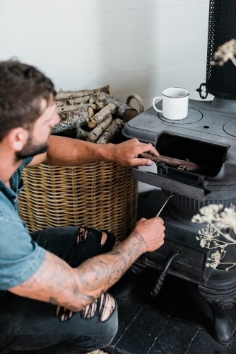 vertical shot of a man preparing a wood stove - Australian Stock Image