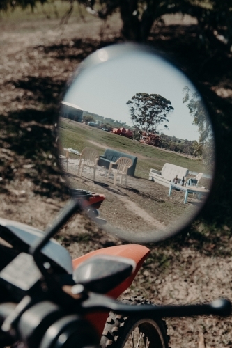 Vertical shot of a reflection of plastic chairs and sofas from the motorcycle's rear mirror - Australian Stock Image