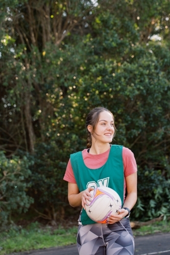 Vertical shot of a woman holding a ball looking away wearing her sportswear - Australian Stock Image