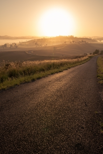 Vertical shot of an empty road heading toward hills at dawn