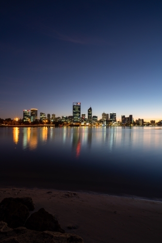 vertical shot of buildings reflecting in a lake with black, blue and white skies about - Australian Stock Image