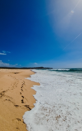 Vertical shot of gentle waves lapping sand at the beach - Australian Stock Image