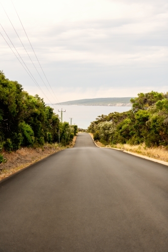 vertical view of road leading down to the ocean - Australian Stock Image