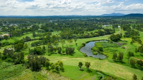 Vibrant green summer landscape showing a golf course and hills in the distance - Australian Stock Image