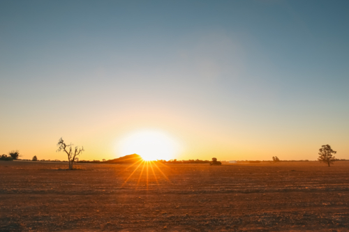 Vibrant sunburst as sun sets behind Pyramid Hill rock formation in Central Victoria - Australian Stock Image