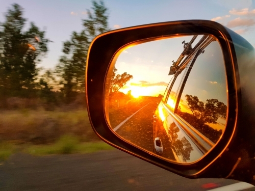 Vibrant sunset reflected in side rear vision mirror of vehicle - Australian Stock Image