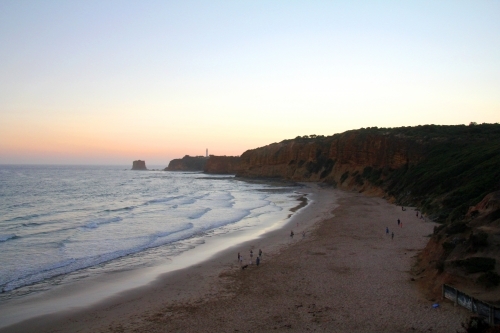 View along beach towards lighthouse at dusk - Australian Stock Image