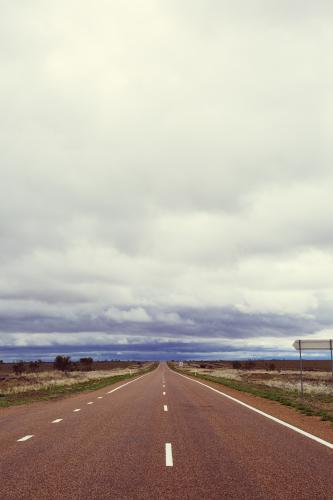 View down a straight flat sealed road in a remote location - Australian Stock Image