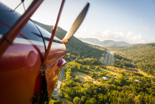 View from biplane approaching airstrip through tropical mountain valley in late afternoon light. - Australian Stock Image