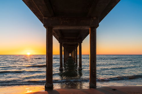 View from down under Brighton Jetty while standing on beach during sunset on summer evening - Australian Stock Image