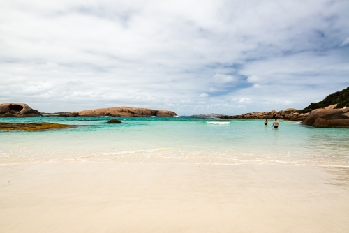 View of a beautiful secluded little beach with swimmers and rocky islands islands - Australian Stock Image