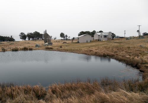 View of a rural farm house across a dam - Australian Stock Image