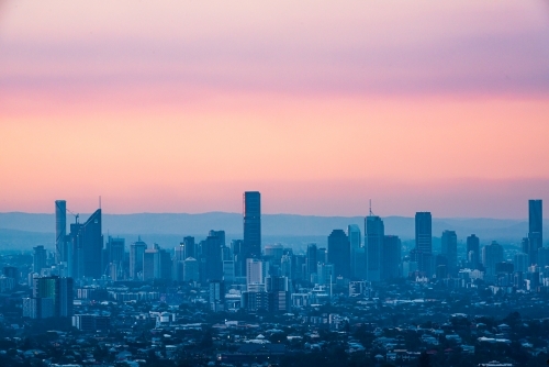 View of Brisbane City skyline from Mt Gravatt Lookout with colourful smoke haze in the sunset - Australian Stock Image