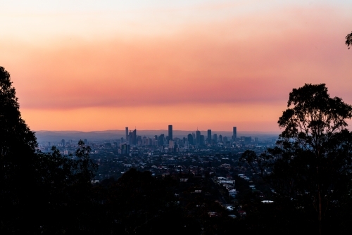 View of Brisbane City skyline with colourful orange smoke haze in the sunset