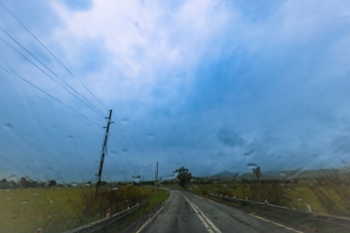 View of countryside on dark stormy day through windshield of vehicle - Australian Stock Image