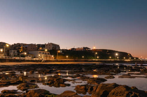 View of Newcastle city at night over rock pools at low tide - Australian Stock Image