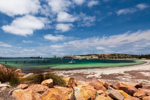 View of Port across a bay with colourful rock wall in foreground - Australian Stock Image