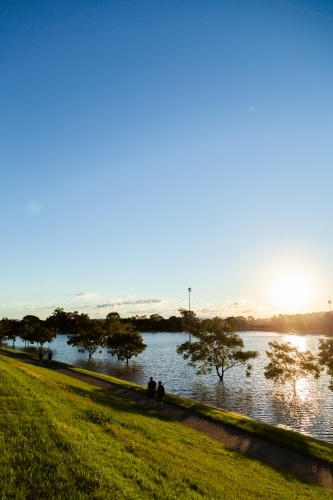 View of sunlight shining off water during flood as it rises up the levee bank - Australian Stock Image