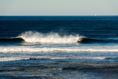 View of surfers with a wave breaking off Surfers Point - Australian Stock Image