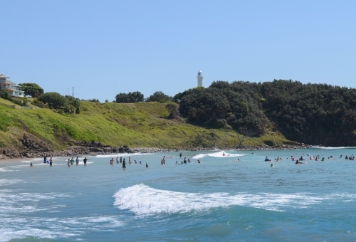 View of swimmers at Main Beach, Yamba, with lighthouse in background - Australian Stock Image