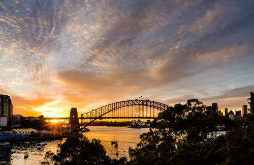 View of Sydney Harbour Bridge with  Opera House  and sun rising with colourful sky cloud patterns.