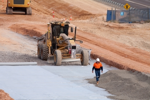 View of workers and heavy machinery on a road construction worksite - Australian Stock Image