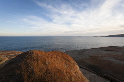 View over flat sea from the orange Remarkable Rocks at sunset - Australian Stock Image