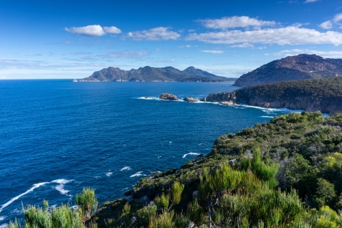 View over ocean and mountains with blue sky and clouds at Freycinet Peninsula - Australian Stock Image