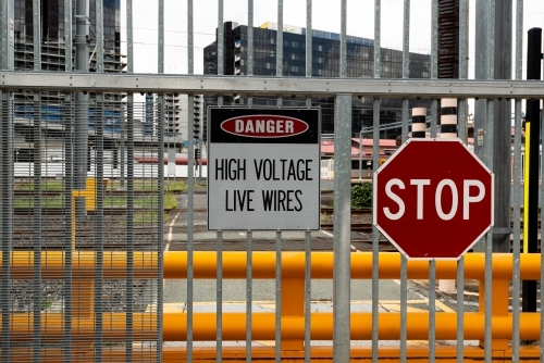View through barred, signed metal gates with rail lines and buildings - Australian Stock Image