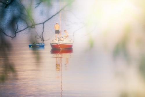 View through trees of people on small sailing boat on the Swan River - Australian Stock Image