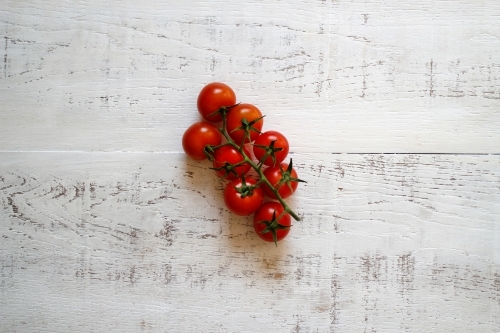 Vine riperned tomatoes on a white wooden background - Australian Stock Image