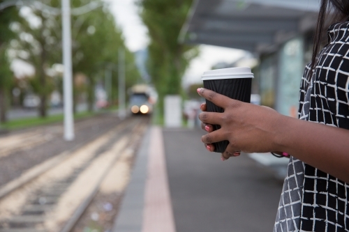 Waiting for the Tram holding takeaway cup - Australian Stock Image