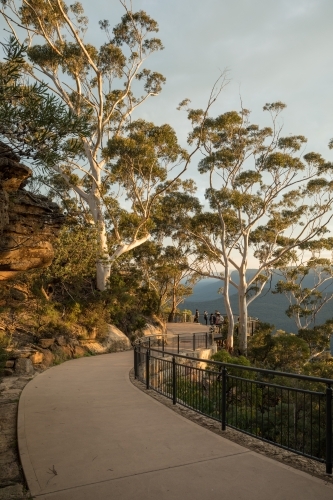 Walking path in bushland with safety fence, gumtrees and distant walkers - Australian Stock Image