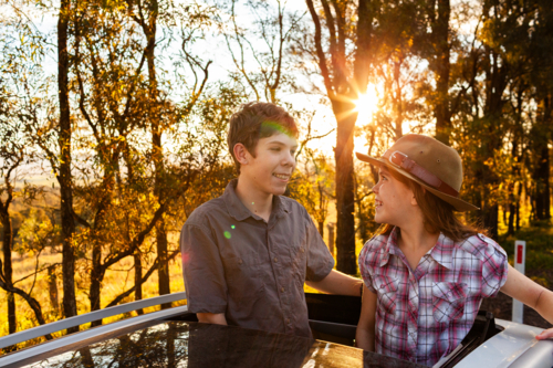 Warm light over country Aussie siblings a boy and girl looking out car sunroof - Australian Stock Image