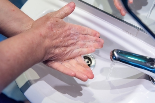 Washing hands with soap and water at basin - Australian Stock Image
