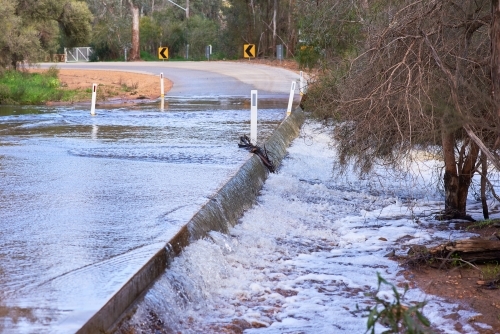 Water flowing over a floodway on a rural road. - Australian Stock Image